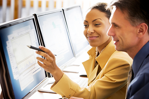 Woman shows man data on computer screen